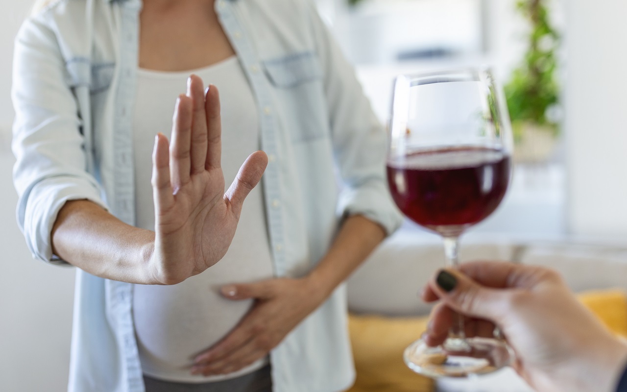 Kobieta w ciąży, która zdecydowanym gestem odmawia alkoholu